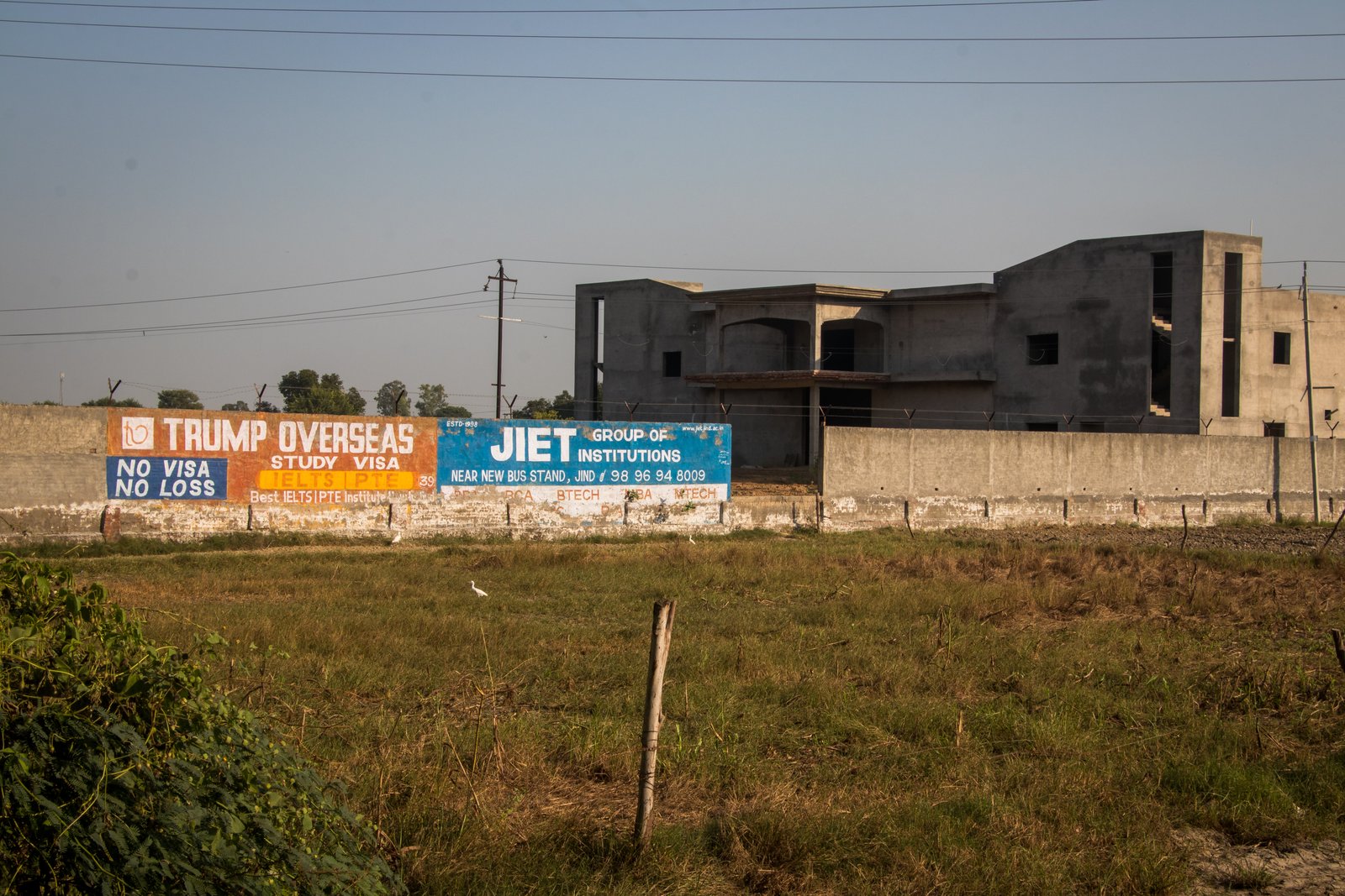 This image shows ads of foreign consultants painted on the boundary walls of an under-construction building near Taloda village.