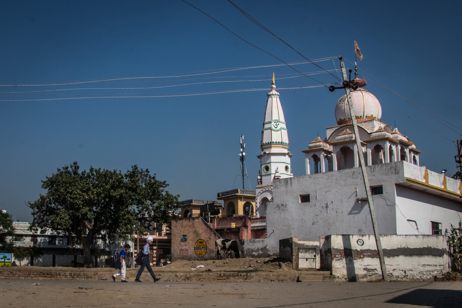 This image shows boys in school uniform walking past a deserted neighbourhood at Dhatrath village in Jind, Haryana.